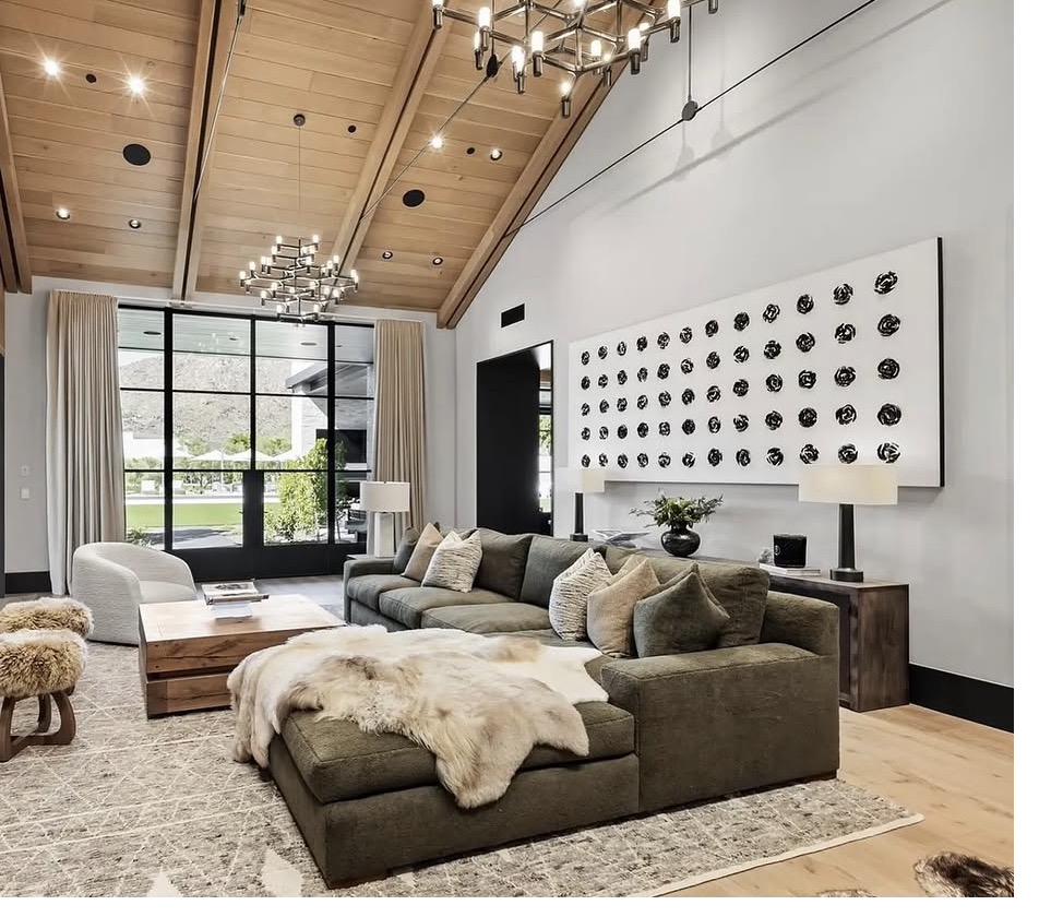 Large-scale modern artwork featuring bold black sculptural rosettes on white canvas displayed in luxury living room with vaulted wood ceiling