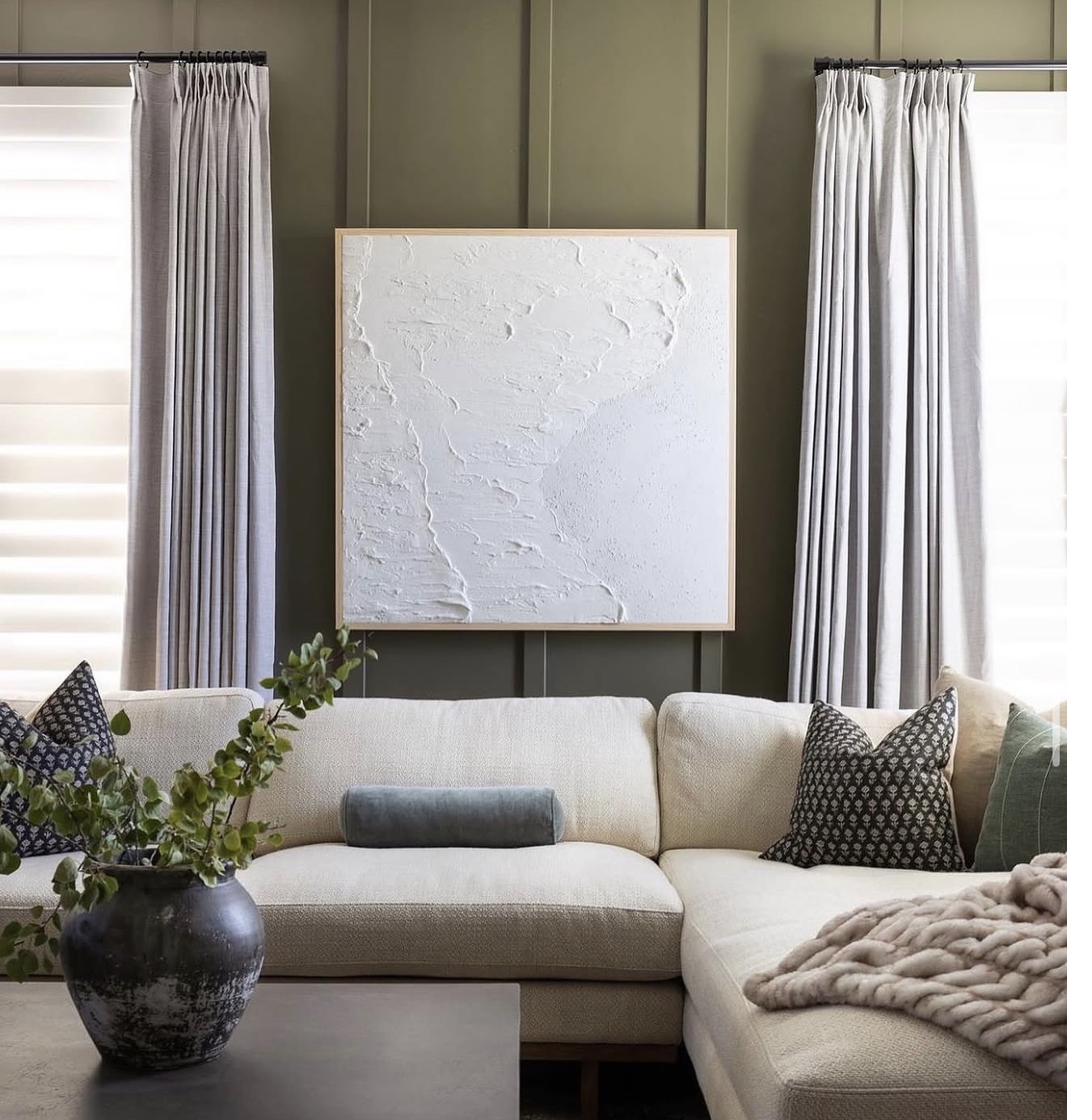 Large white textured abstract painting above sectional sofa in modern living room