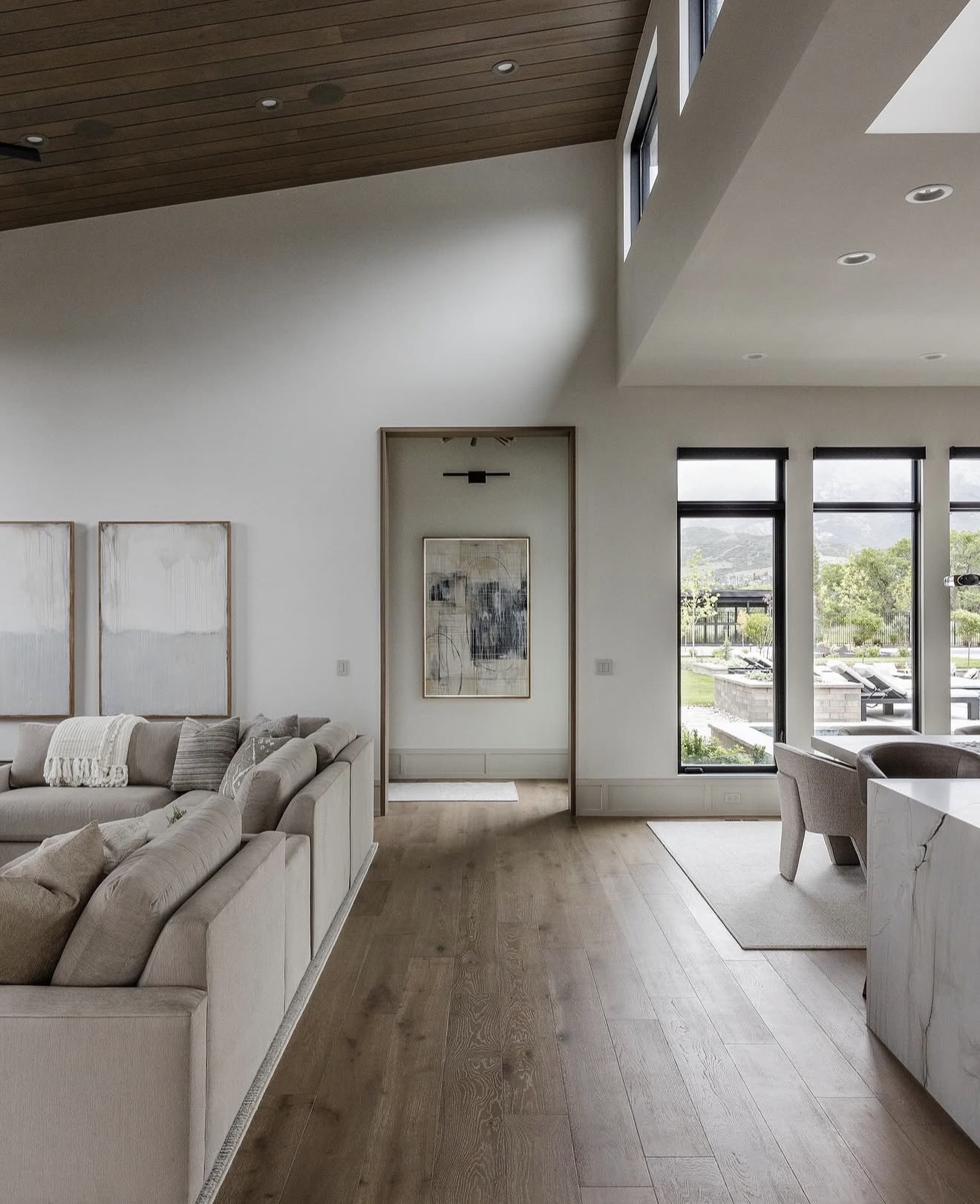 Multiple custom artworks including neutral diptych and framed abstract displayed in open-plan luxury home with vaulted wood ceiling and panoramic mountain views