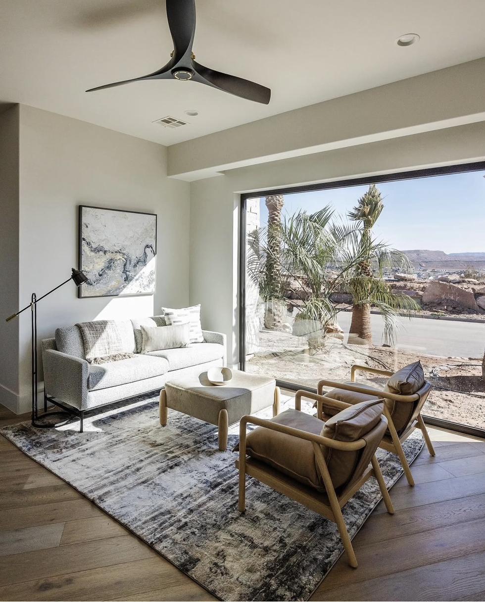 Abstract fluid painting in gray and white marble-like tones displayed in modern desert living room with panoramic mountain views through floor-to-ceiling window