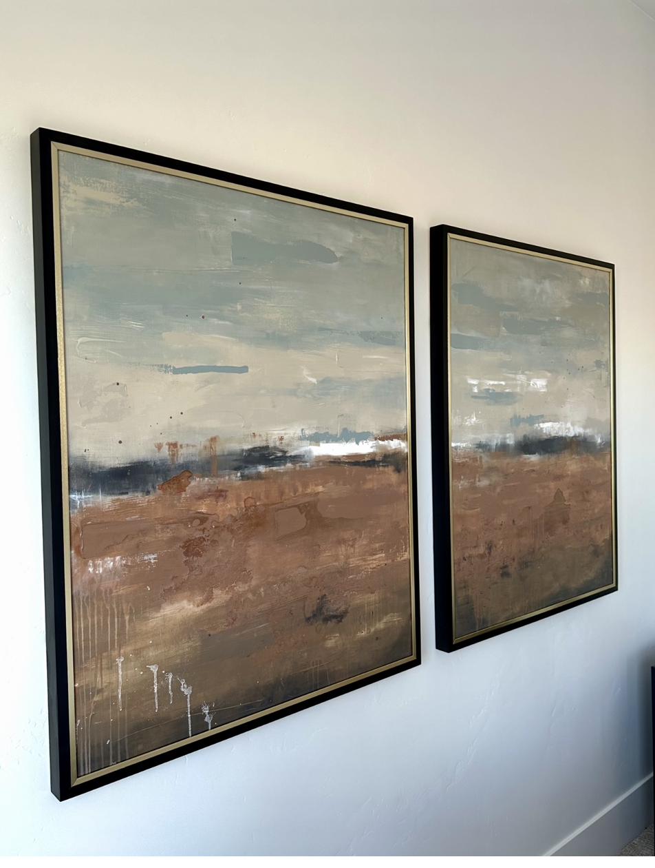 Diptych of abstract landscape paintings in earth tones featuring sienna brown and soft gray horizon lines with paint drips in black and gold frames