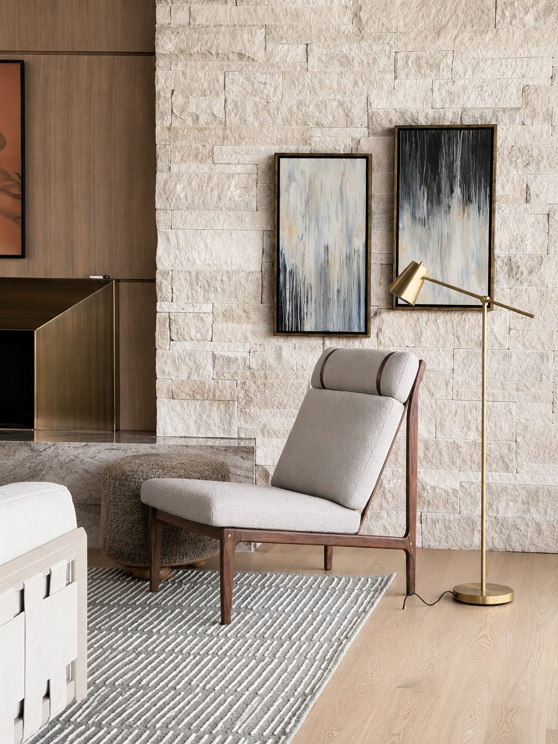 Pair of vertical abstract paintings with dripping streaks of slate blue, gray, and black hung on a limestone wall above a lounge chair